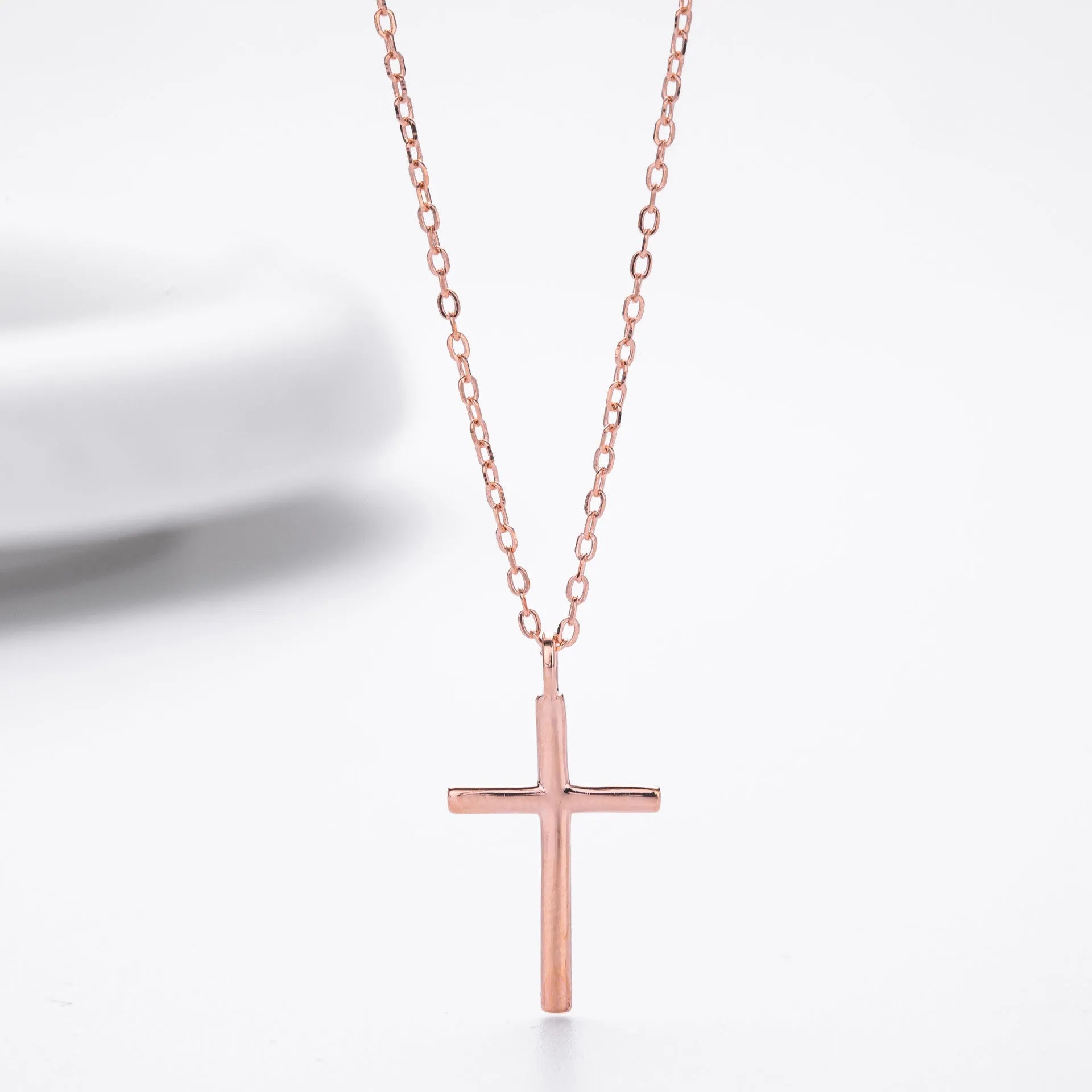 Sterling silver cross necklace with O-shaped chain in gold plating on display