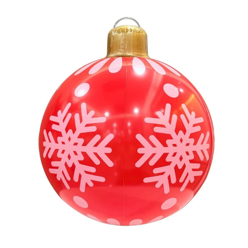 Large red inflatable Christmas ball with snowflake design and LED lights in outdoor garden setting