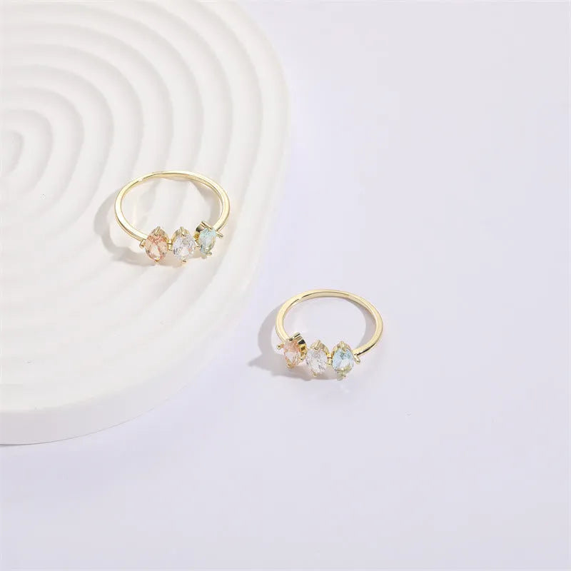 Geometric triangle birthstone ring with horse eye design and tricolour zircon stones on woman's hand