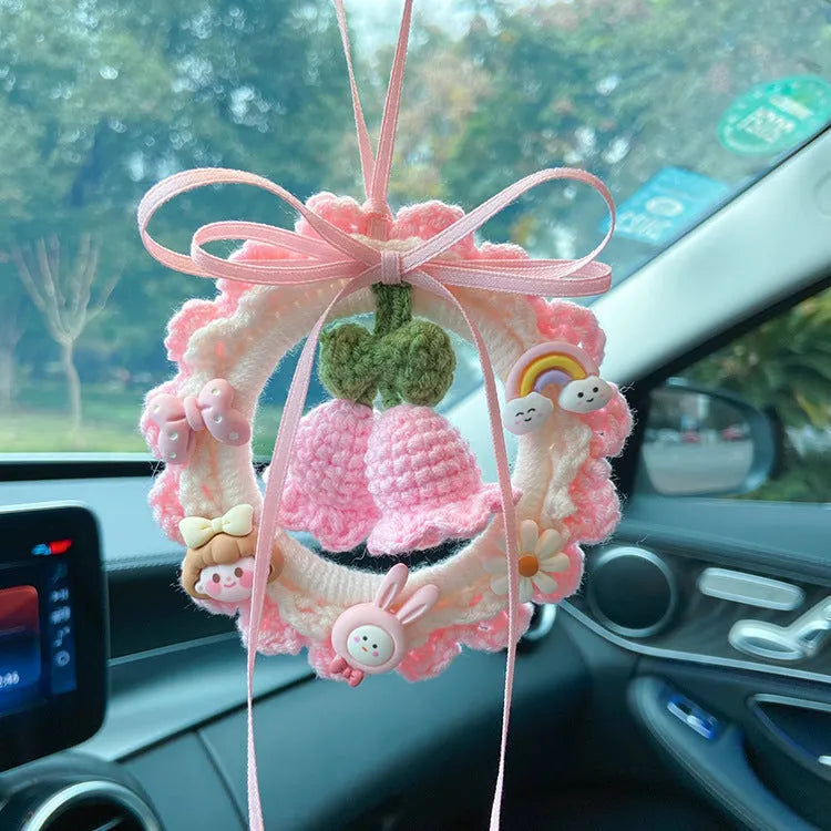 Handwoven wool bell orchid car pendant in green, hanging with dreamcatcher charm.