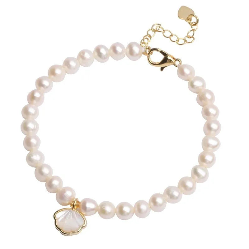 Women's freshwater pearl bracelet with central fan shell design on a wrist, showing elastic and chain fastening options.