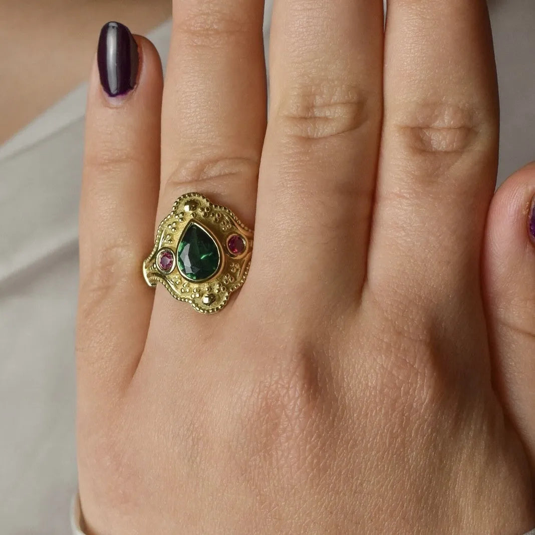 A gold-coloured women's ring with a geometric shape on a plain background.