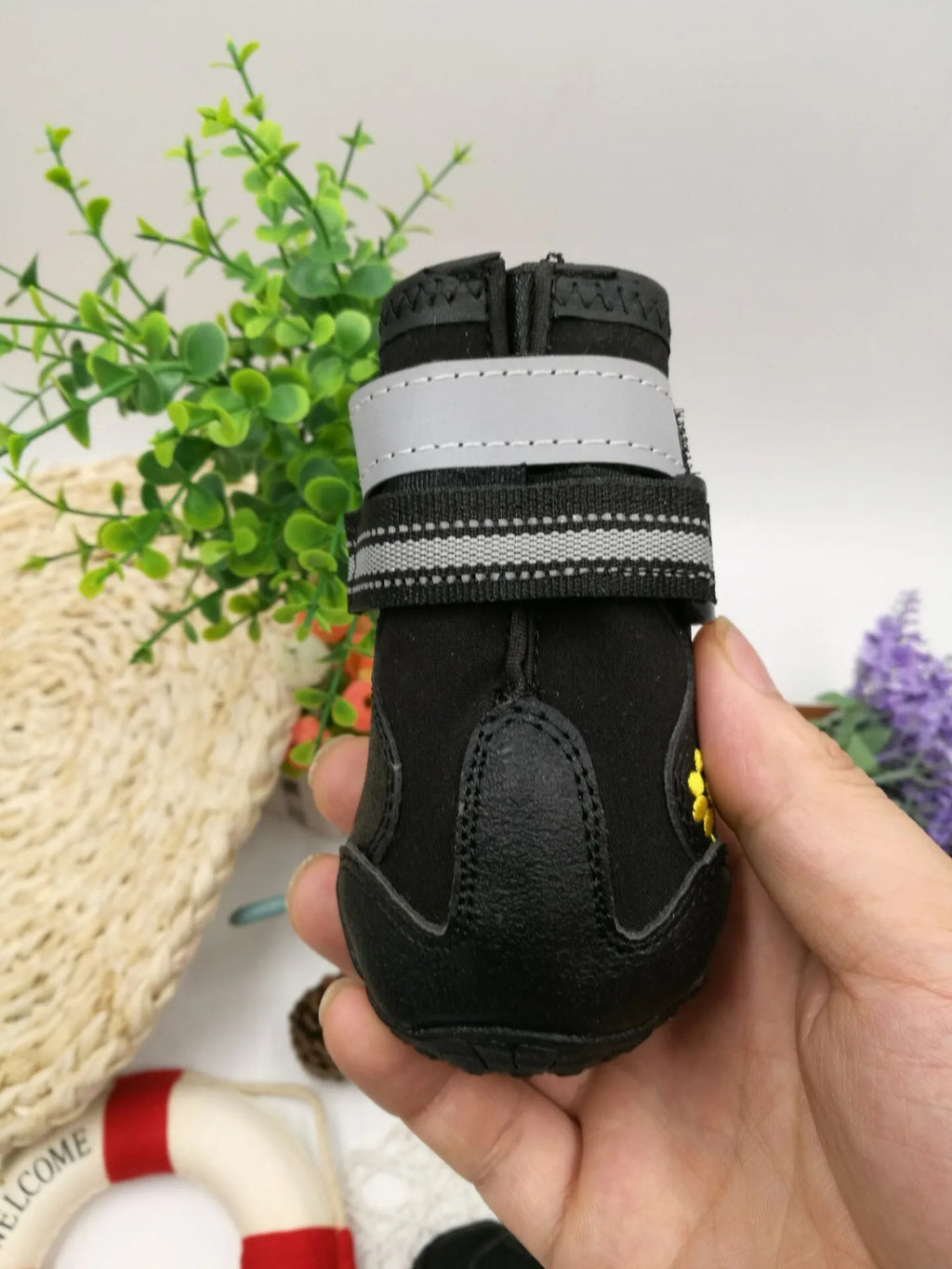 Black dog shoes with waterproof PVC sole and adjustable fuzzy belt on a dog's paw