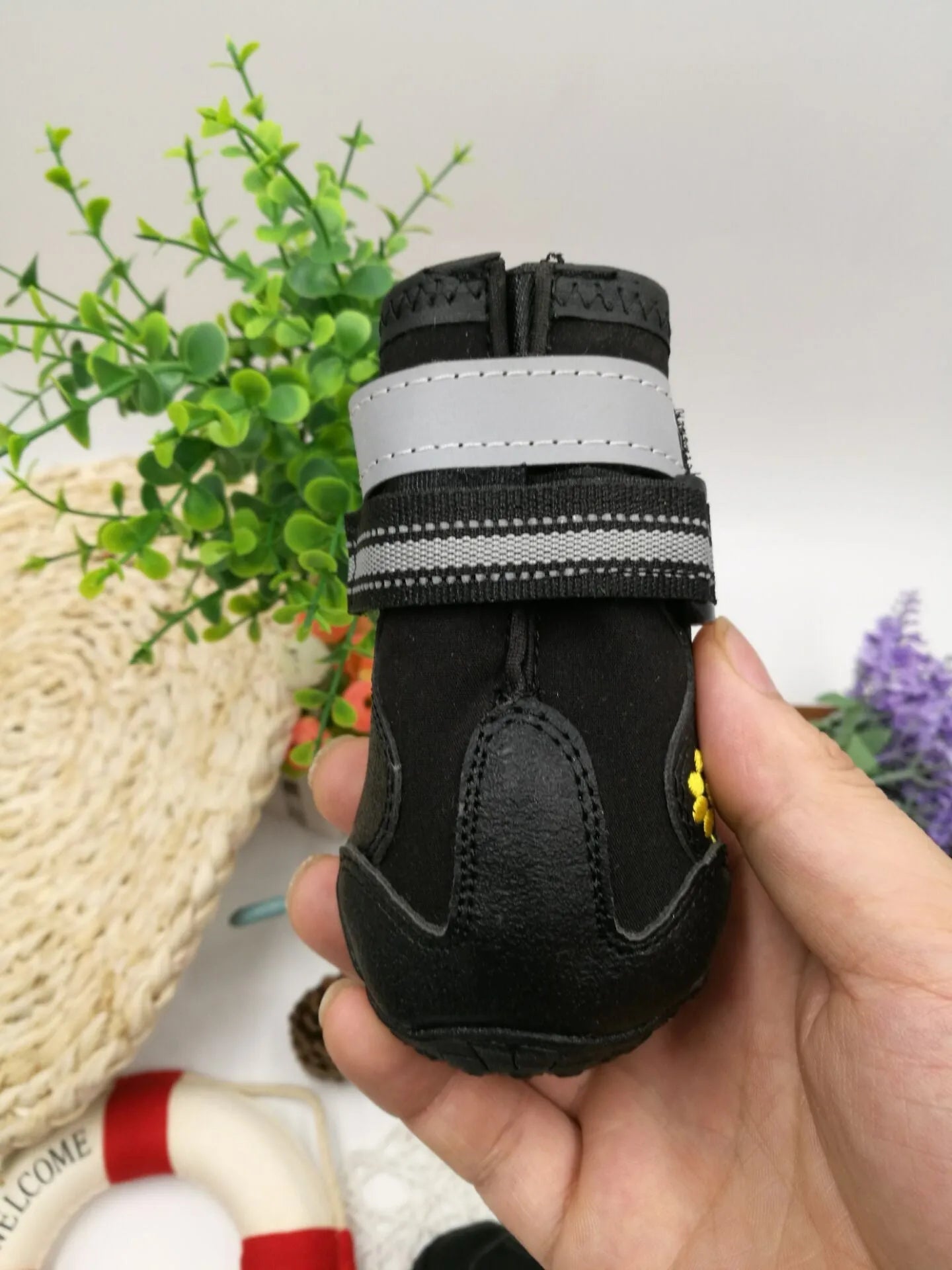 Black dog shoes with waterproof PVC sole and adjustable fuzzy belt on a dog's paw