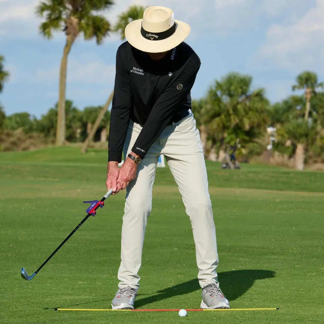 Plastic golf swing plane simulator training aid on practice surface