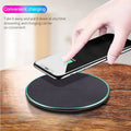 Black Qi wireless charging pad for iPhone 11 placed on a wooden surface.