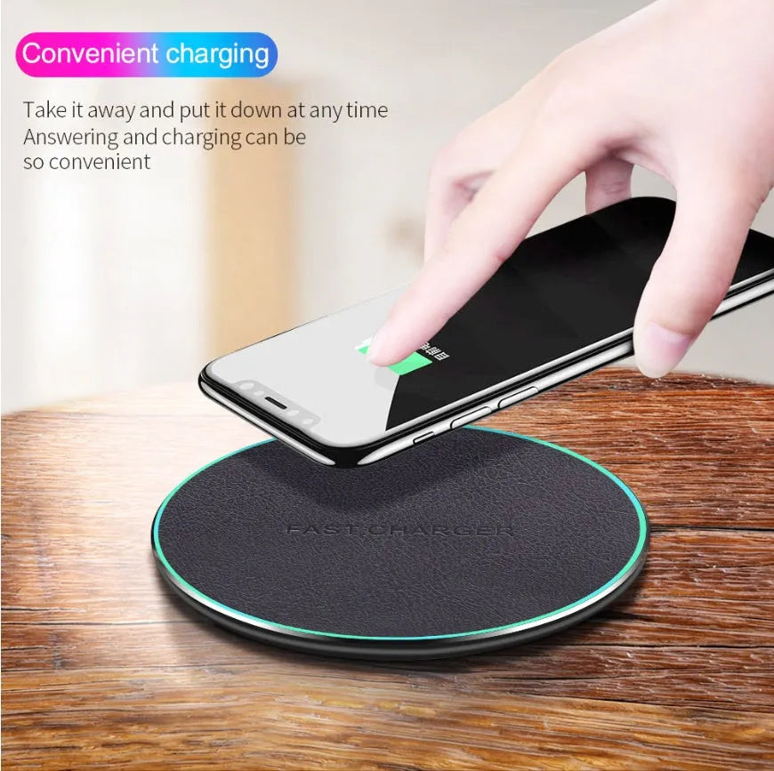 Black Qi wireless charging pad for iPhone 11 placed on a wooden surface.