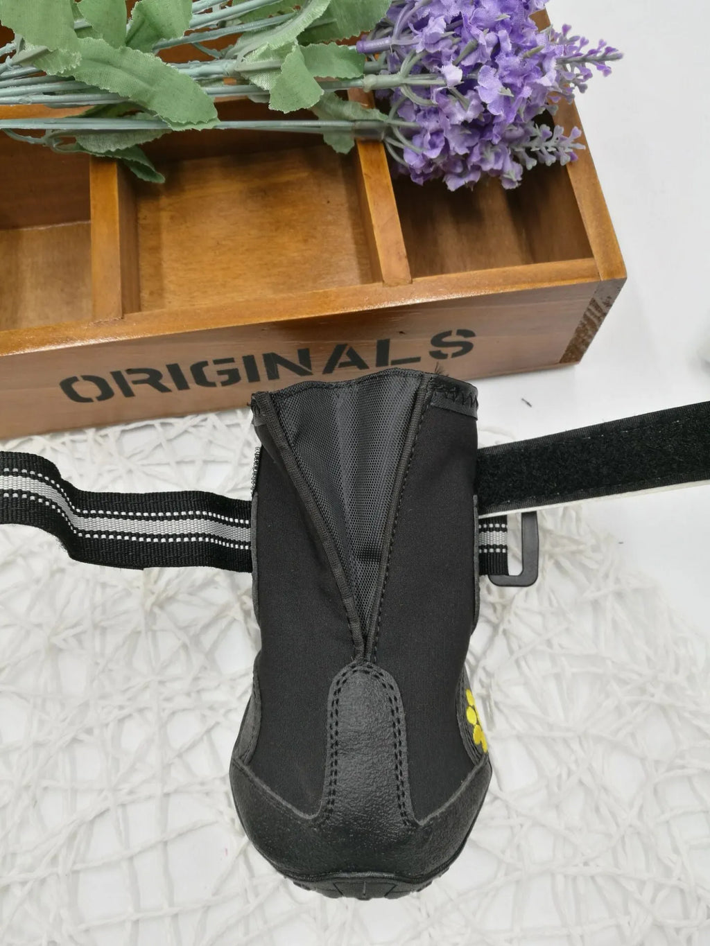 Black dog shoes with waterproof PVC sole and adjustable fuzzy belt on a dog's paw