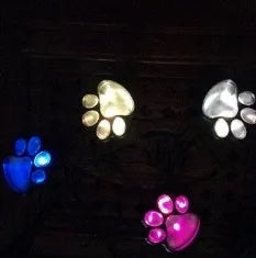 Set of four black bear paw print solar LED garden lights with a central solar panel pole on grass.