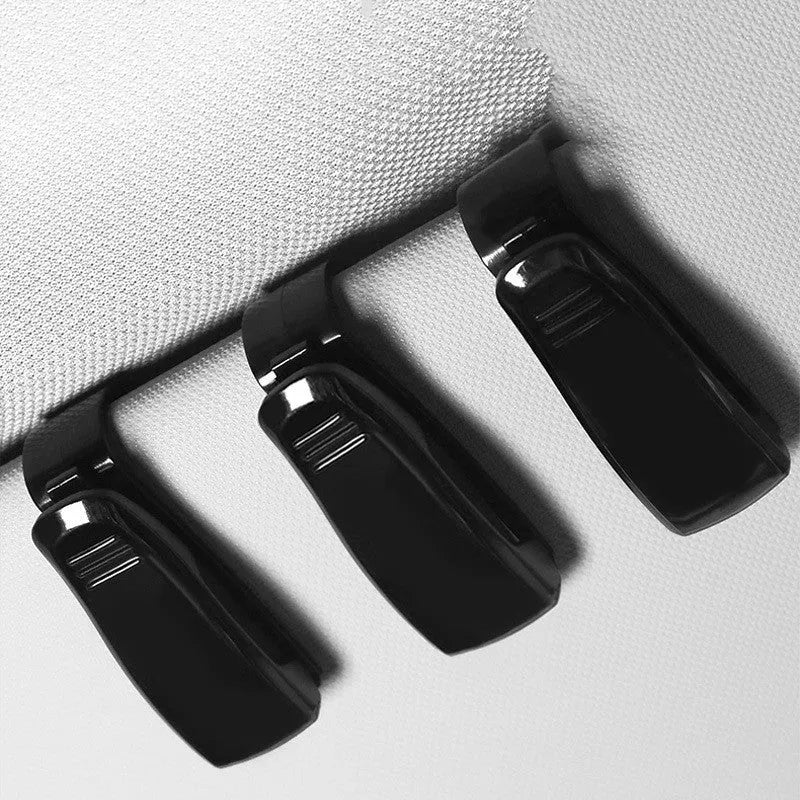 Black plastic multifunctional clip for mounting on a car sunshade to hold glasses, tickets, and ID cards.