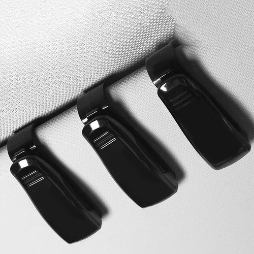 Black plastic multifunctional clip for mounting on a car sunshade to hold glasses, tickets, and ID cards.