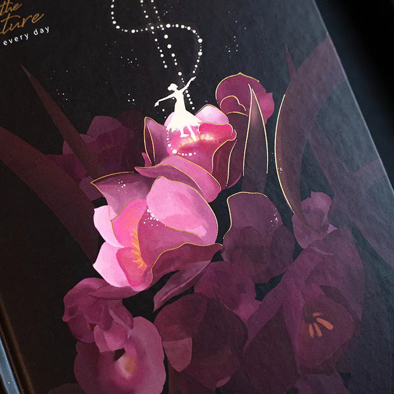 A5 size diary book with a luminous purple cover, open to show pages with colour illustrations.