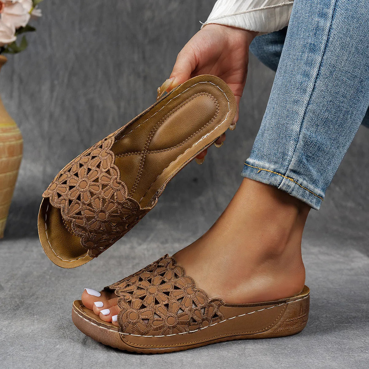 Women's black wedge beach slipper with floral cutouts and fish mouth toe shape on a rubber sole.