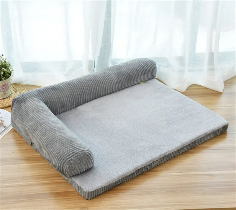 Grey corduroy dog sofa bed with raised sides on a wooden floor, showing its non-slip base.