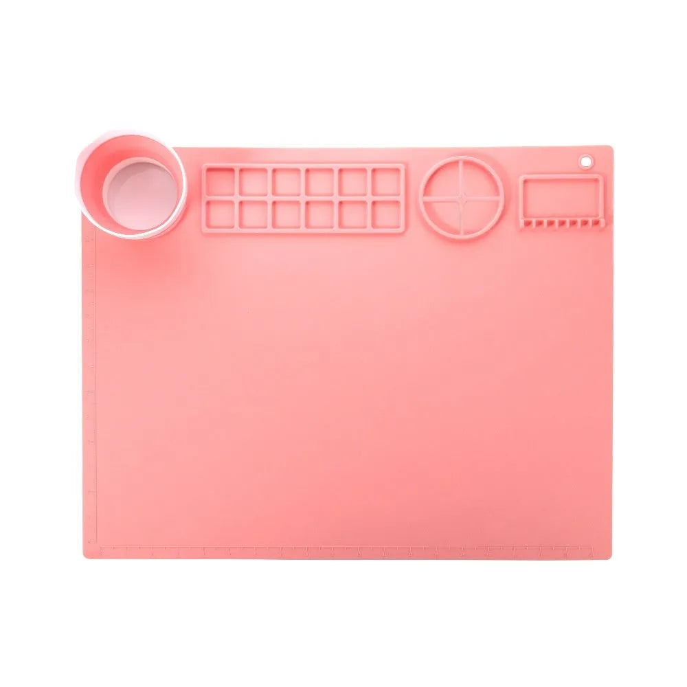 Light blue silicone painting mat with an integrated bowl on one side, positioned on a wooden table.