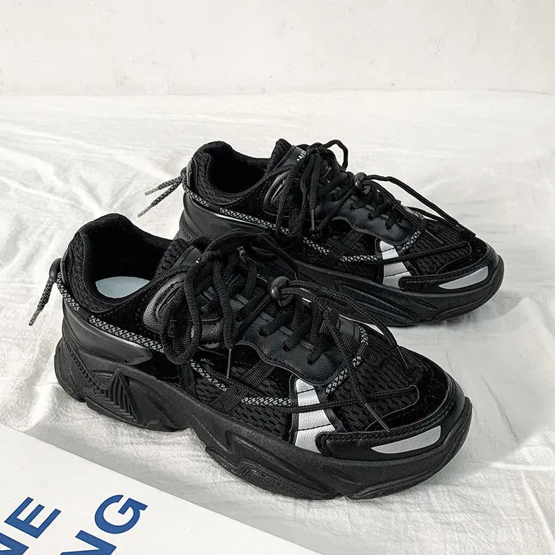 Men's black platform dad shoes with white soles and lace-up front, shown on a grey background.