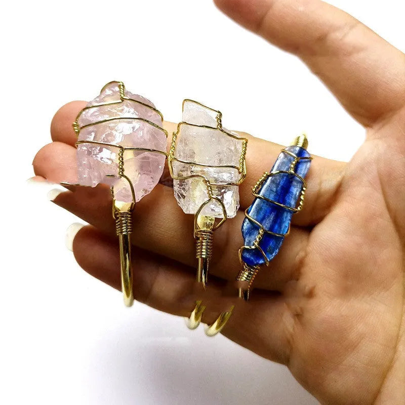 Natural rough crystal bracelet with geometric gold metal winding on a wrist.