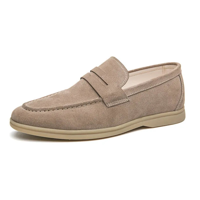 Men's brown leather slip-on casual shoes with round toe and rubber sole on a wooden floor.