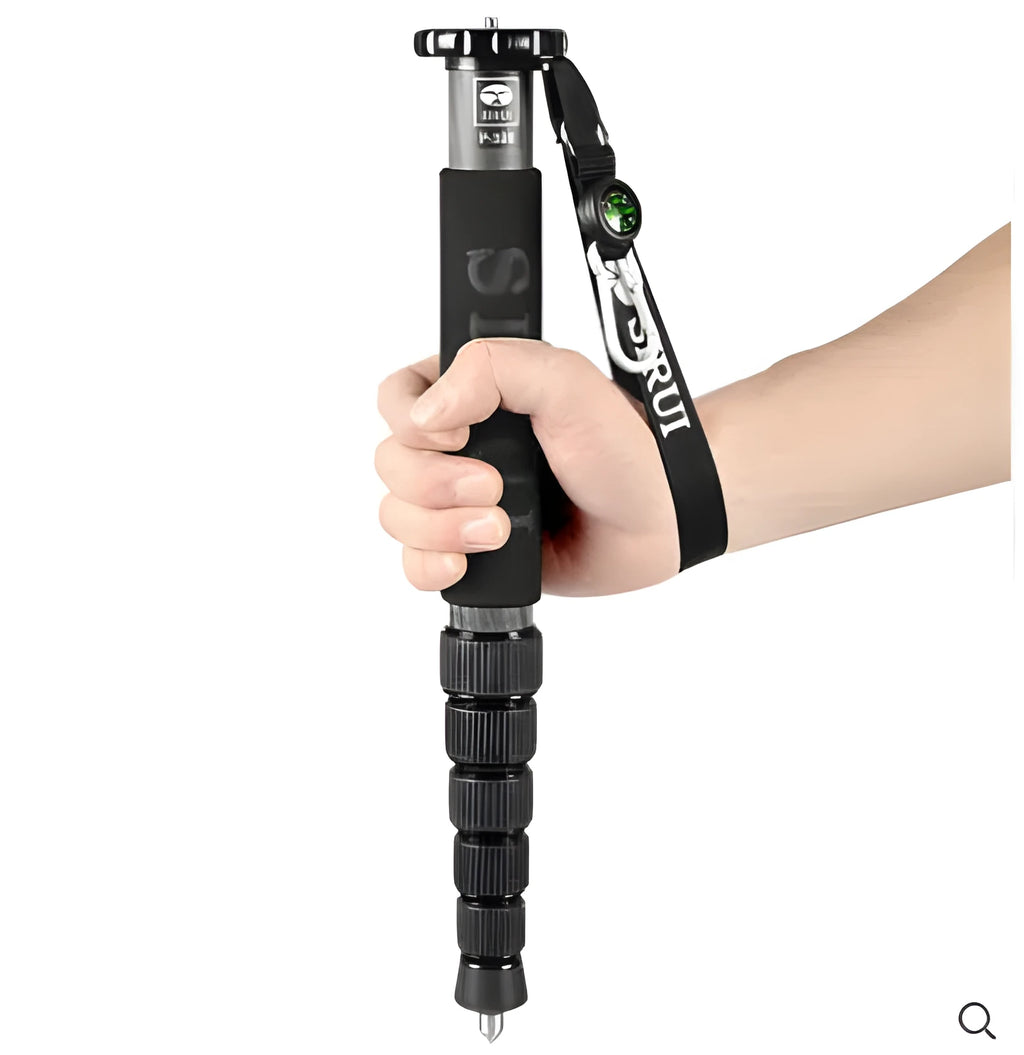 Black carbon fibre telescopic camera monopod extended to full height on a grey background.