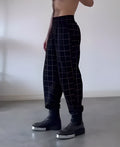 Men's plaid check trousers with apron front panel showing elastic waist and button fly