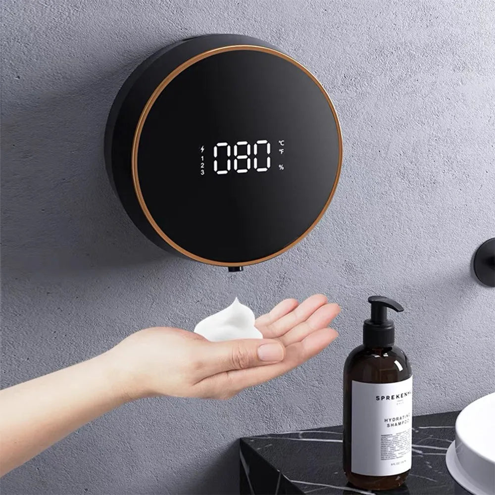 Black automatic sensor soap dispenser mounted on a white bathroom wall, dispensing foam.