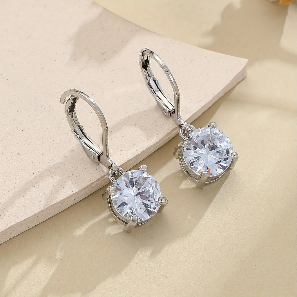 Silver-toned cubic zirconia stud earrings with 4mm round stone in claw setting on white background