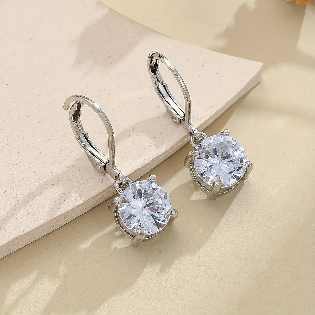 Silver-toned cubic zirconia stud earrings with 4mm round stone in claw setting on white background