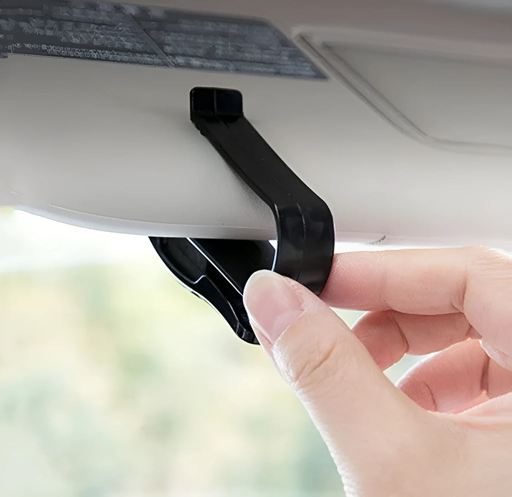 Black plastic multifunctional clip for mounting on a car sunshade to hold glasses, tickets, and ID cards.