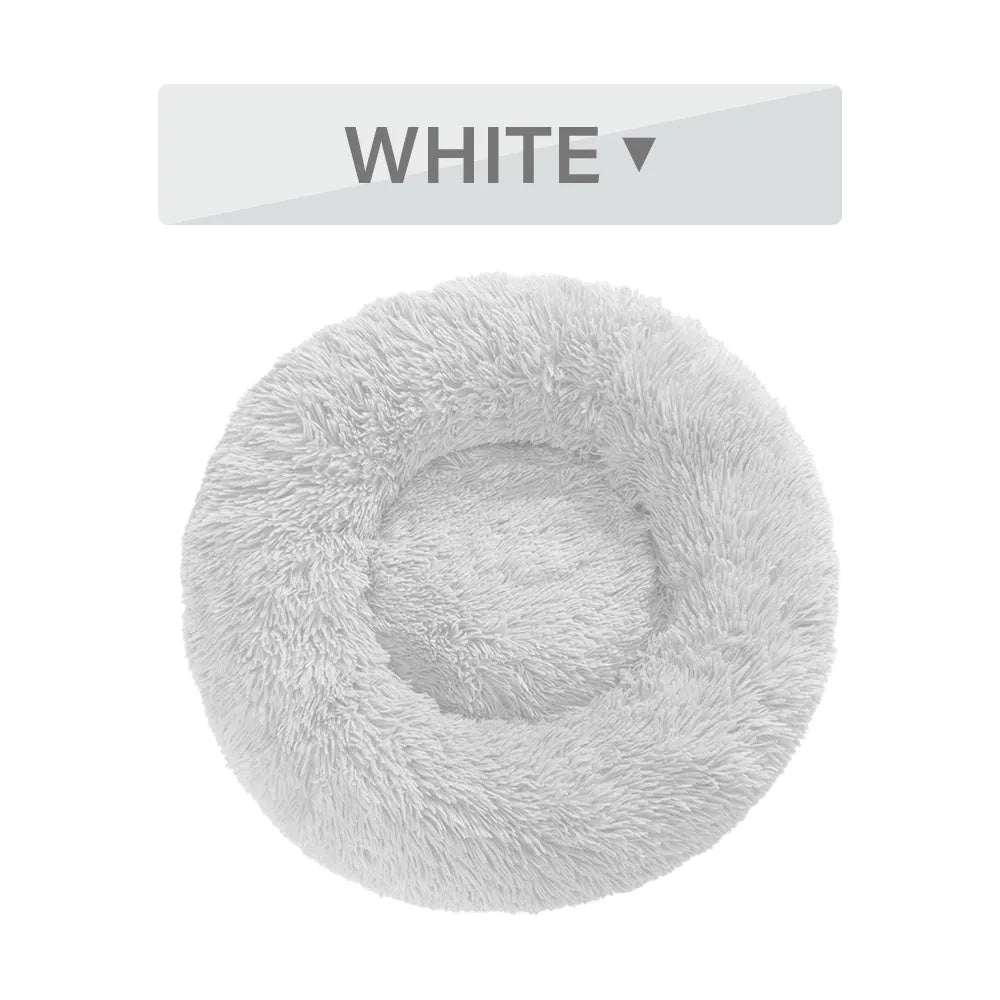 Fluffy long plush donut-shaped pet bed for dogs and cats on a wooden floor.