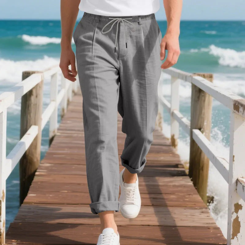 Men's light khaki linen casual trousers with a straight leg and drawstring waistband laid flat.