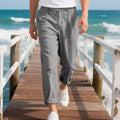 Men's light khaki linen casual trousers with a straight leg and drawstring waistband laid flat.