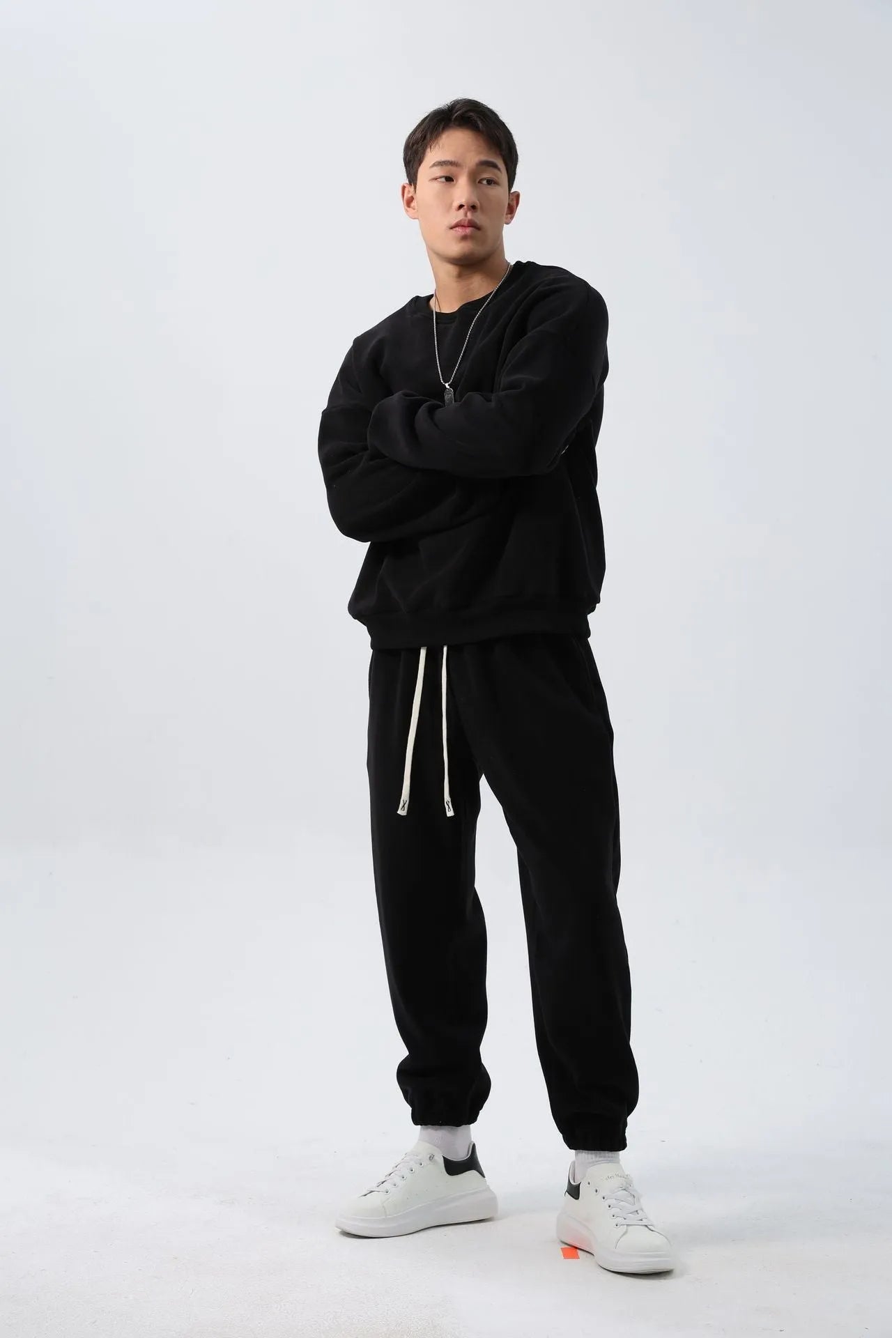 Men's black polar fleece sports suit with loose crew neck jacket and padded trousers on a hanger.
