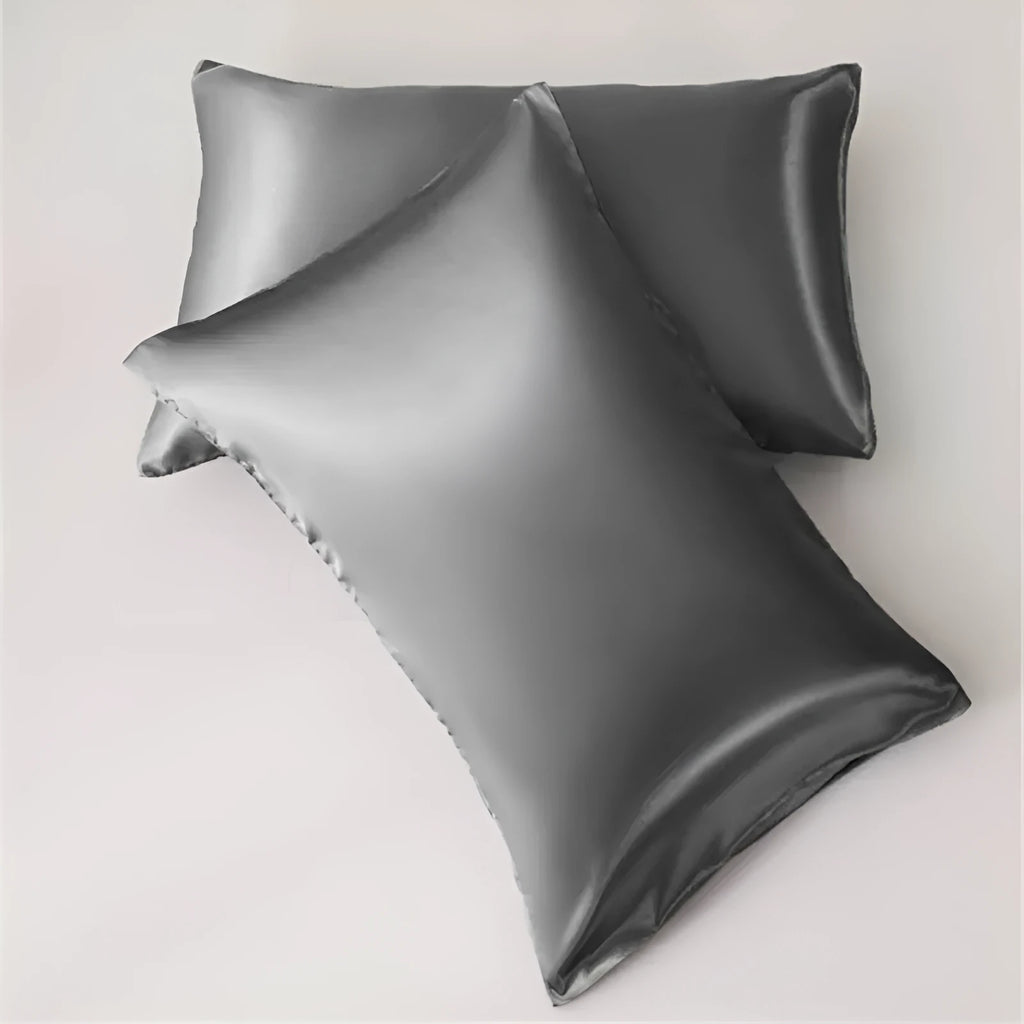 Dark blue polyester satin pillowcase with envelope closure on a bed with white sheets