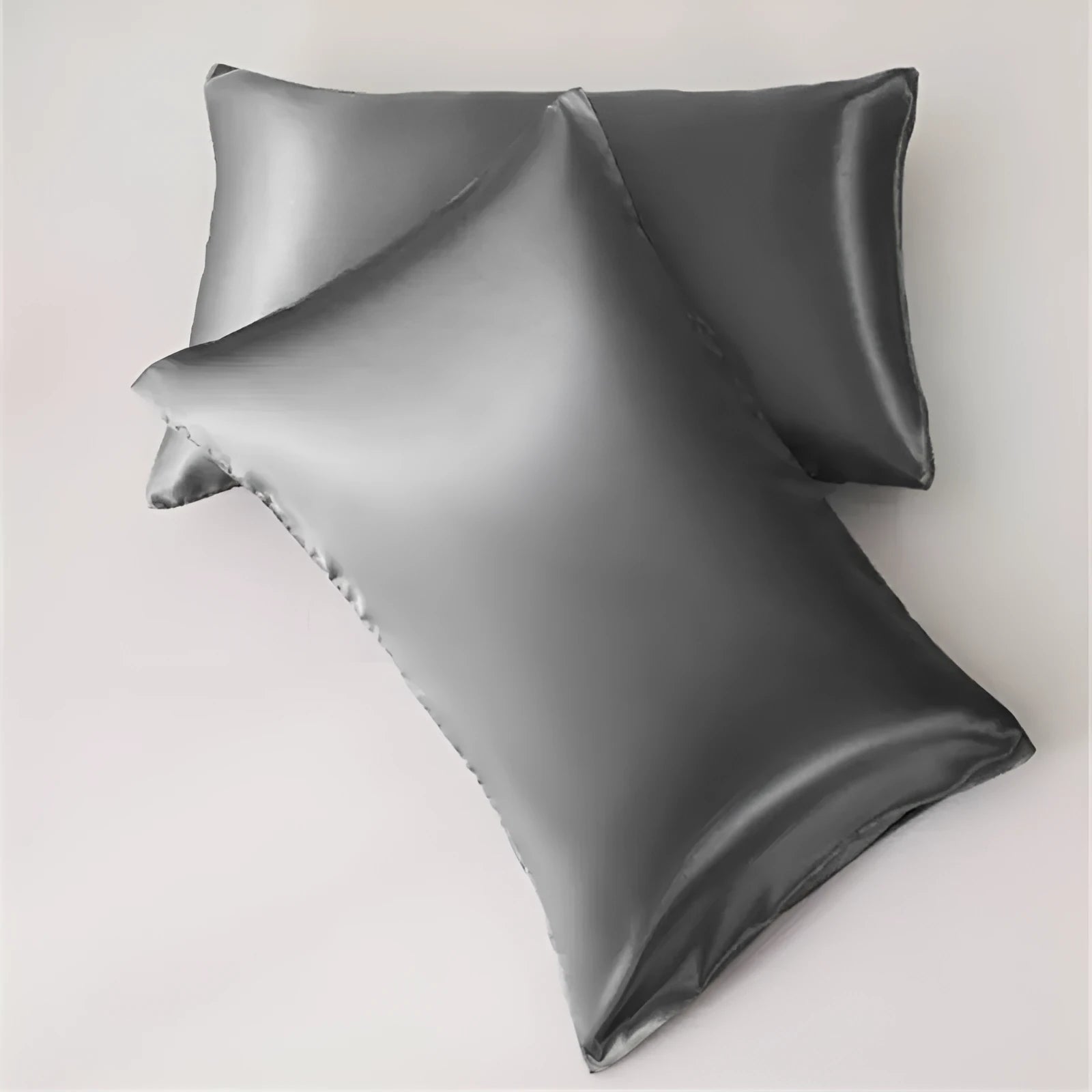 Dark blue polyester satin pillowcase with envelope closure on a bed with white sheets