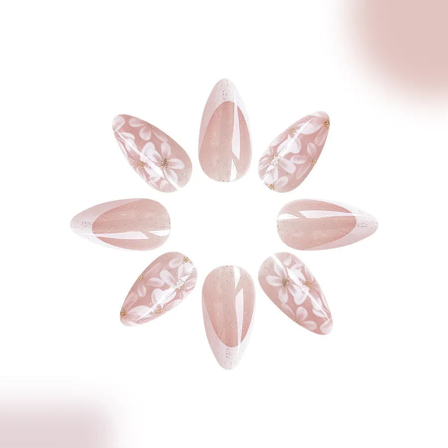 Short almond shaped faux nails with French manicure style and glittery pink flower design.
