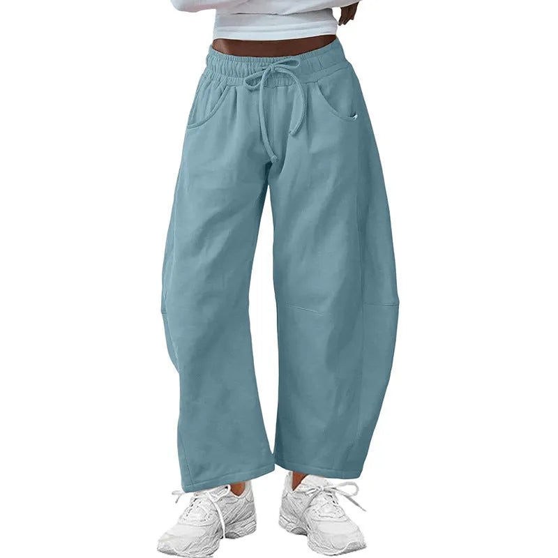 Women's loose grey cropped sweatpants with drawstring waist and side pockets on a hanger.