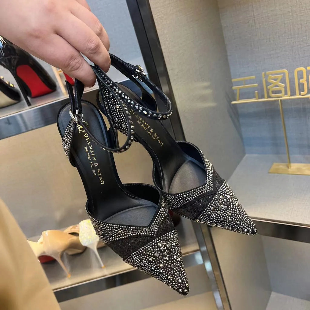 Women's silver high heel shoe with hollow stiletto heel, pointed toe, and bright red sole.