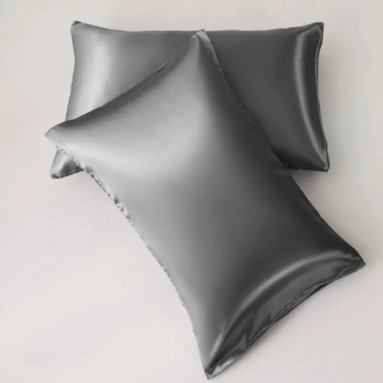 Dark blue polyester satin pillowcase with envelope closure on a bed with white sheets