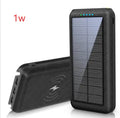 Black portable power bank with wireless charging pad on top, three USB ports, and an LED flashlight.