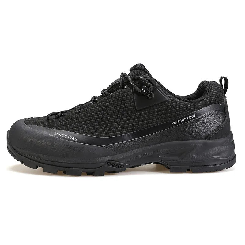 Men's low-top hiking boot in black with front lace-up, rubber outsole, and leather mesh upper.