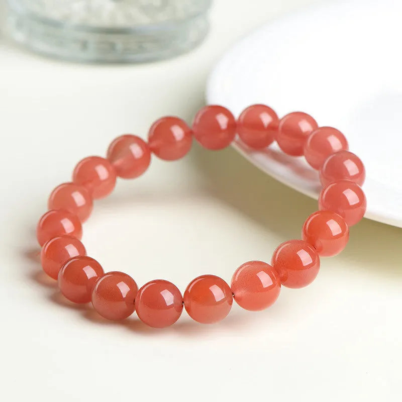 Natural cherry red agate bracelet with polished beads on a white background.