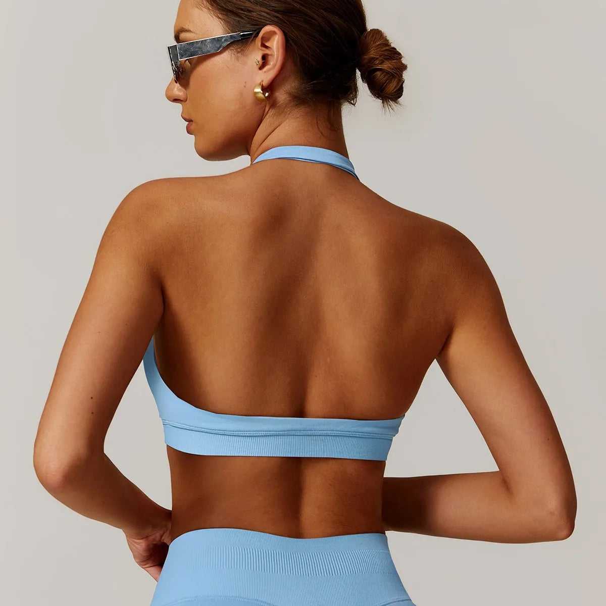 Women's halter-style sports bra in multiple colours, showing hollow back design and removable pads.