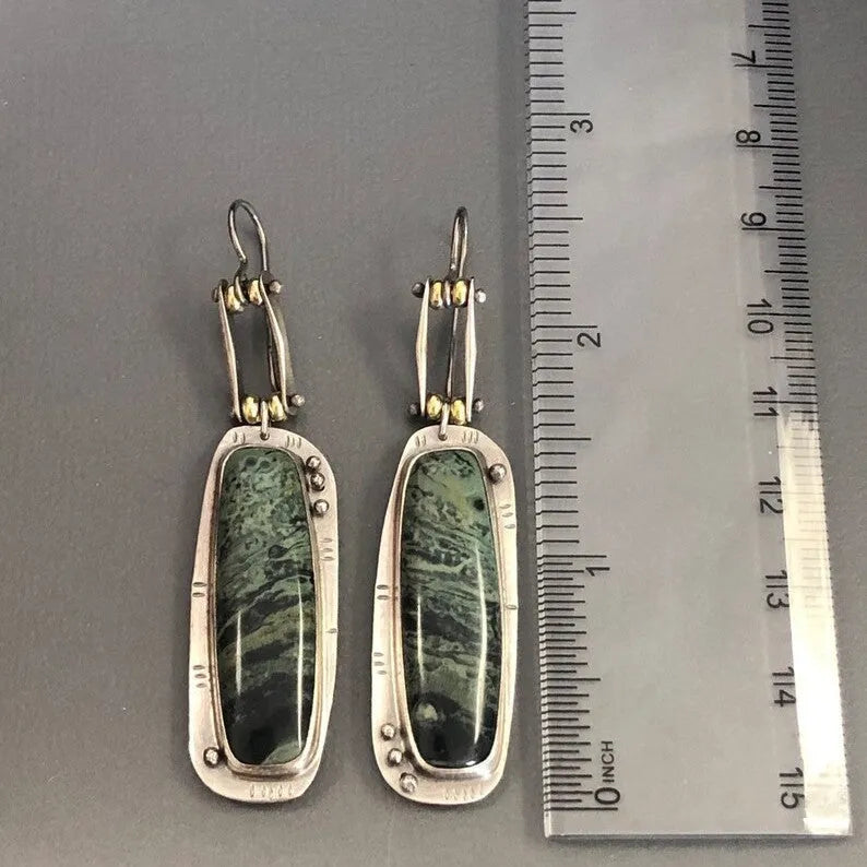 Close-up of women's geometric alloy earrings with a white and grey marble pattern.