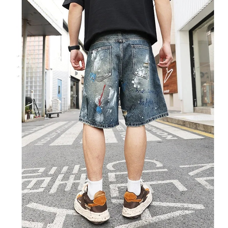 Blue ripped men's denim shorts with graffiti pattern and straight-leg cut.