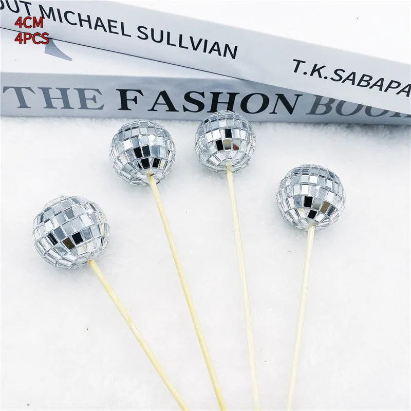 Glass disco ball cake decorations with wooden sticks in multiple sizes on birthday cake