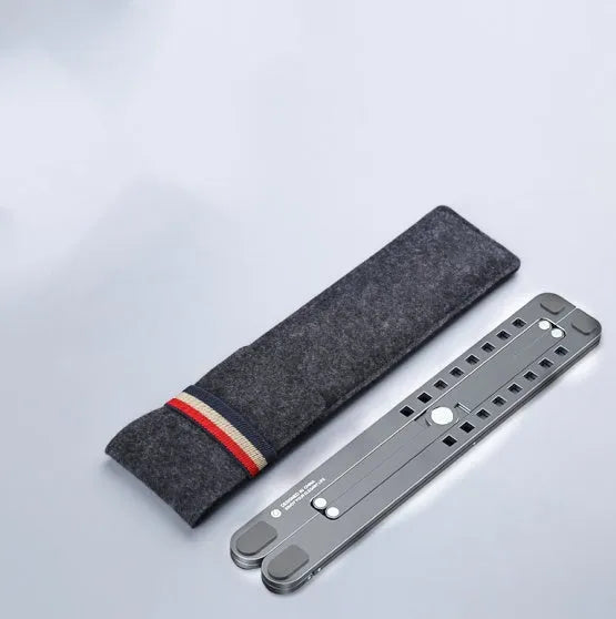 A folded silver aluminium laptop stand next to an open laptop, showing its thin profile and adjustable angle mechanism.