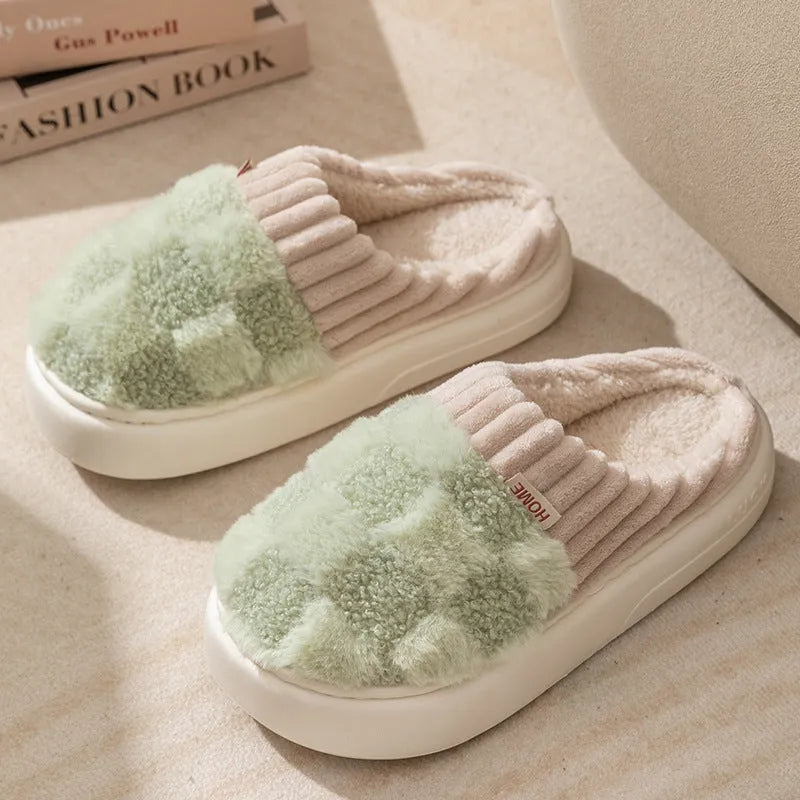 Women's plaid patterned coral velvet indoor slippers with a thick soft sole on a wooden floor.