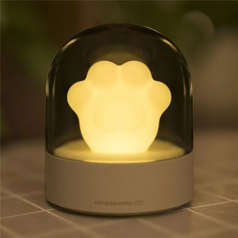 Grey or pink cat paw shaped USB rechargeable night light with musical functions on wooden desktop