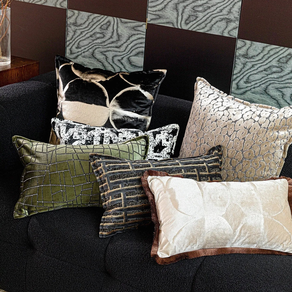 Black and gold abstract pattern decorative cushion with removable cover on a grey sofa.