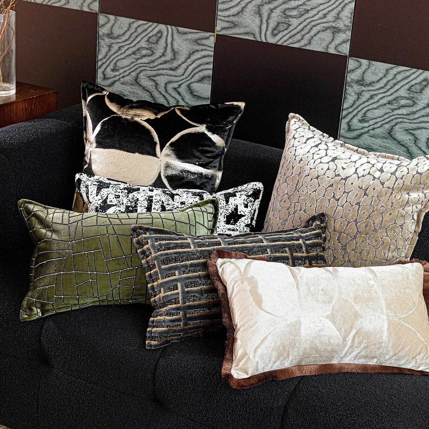 Black and gold abstract pattern decorative cushion with removable cover on a grey sofa.